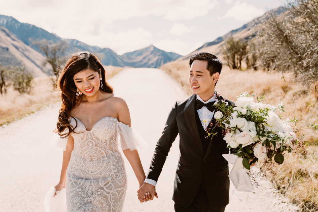 Bride and Groom in Wedding Attire Walking Down a Dirt Road At their Stunning Queenstown Elopement , Is Eloping Right For You? 