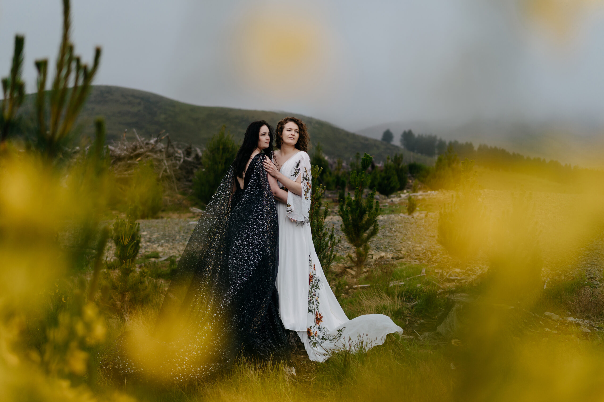 Two brides standing together in the fields during their autumn elopement in Mount Cook National Park