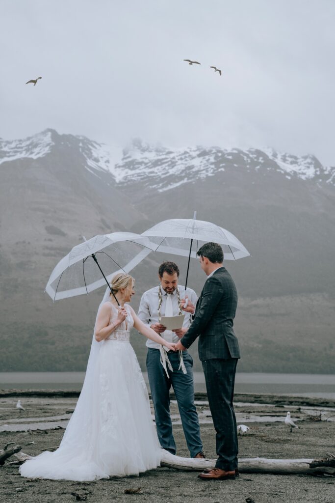 bride and groom under umbrellas with celebrate eloping