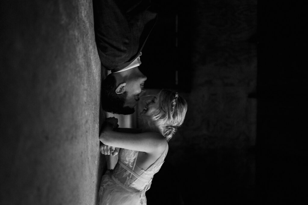 couple in wedding attire laughing at one another on the floor of a bedroom