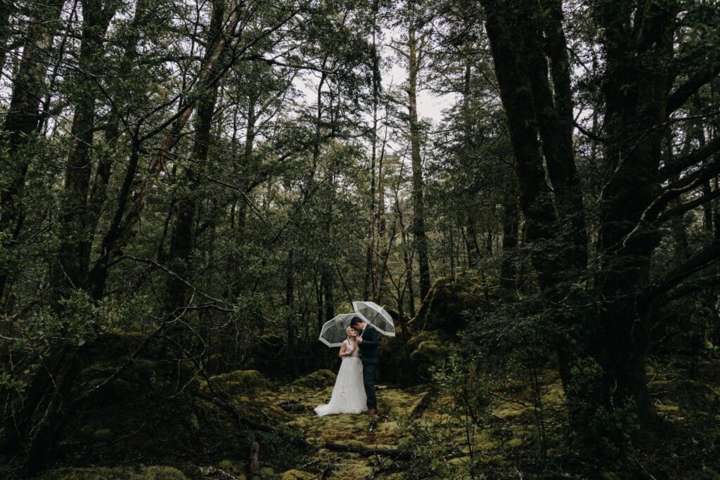 bride and groom holding umbrellas in the forest posing for elopement photographers