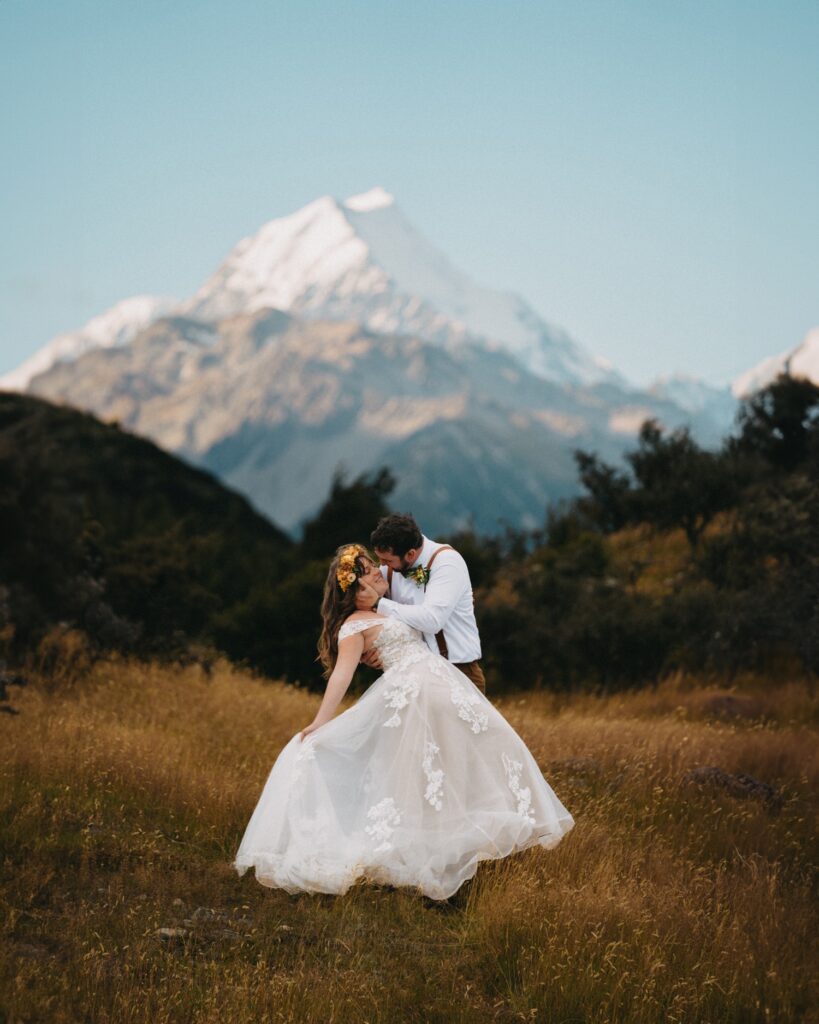 groom dipping bride to kiss in front of mountains in new zealand for elopement photographers