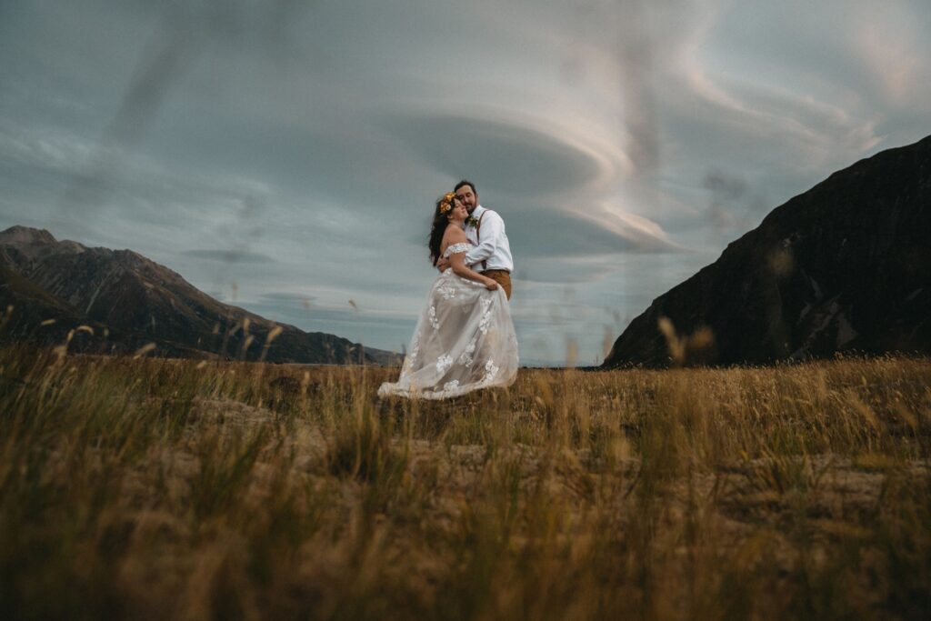 a bride and groom in a stormy field