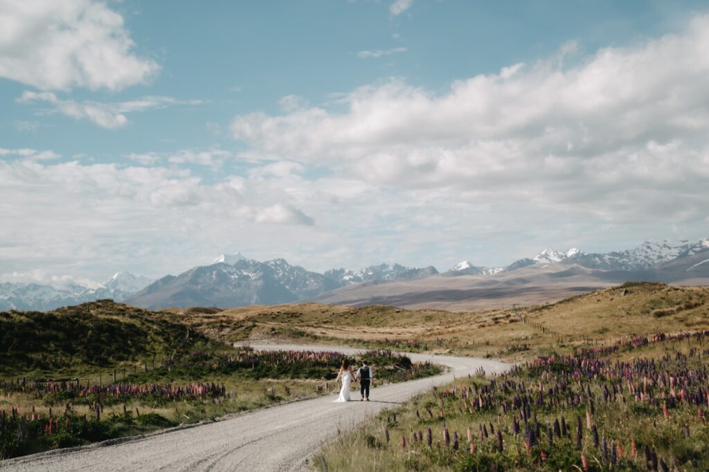 a bride and groom walking down a dusty road 