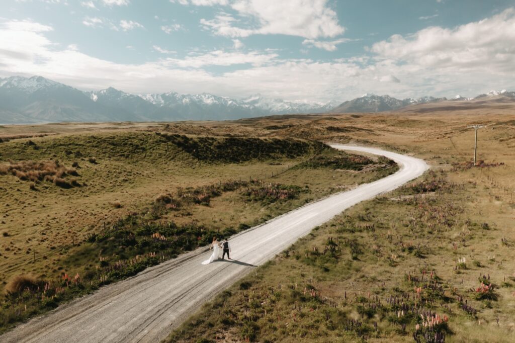 bride and groom running down dirt road in new zealand