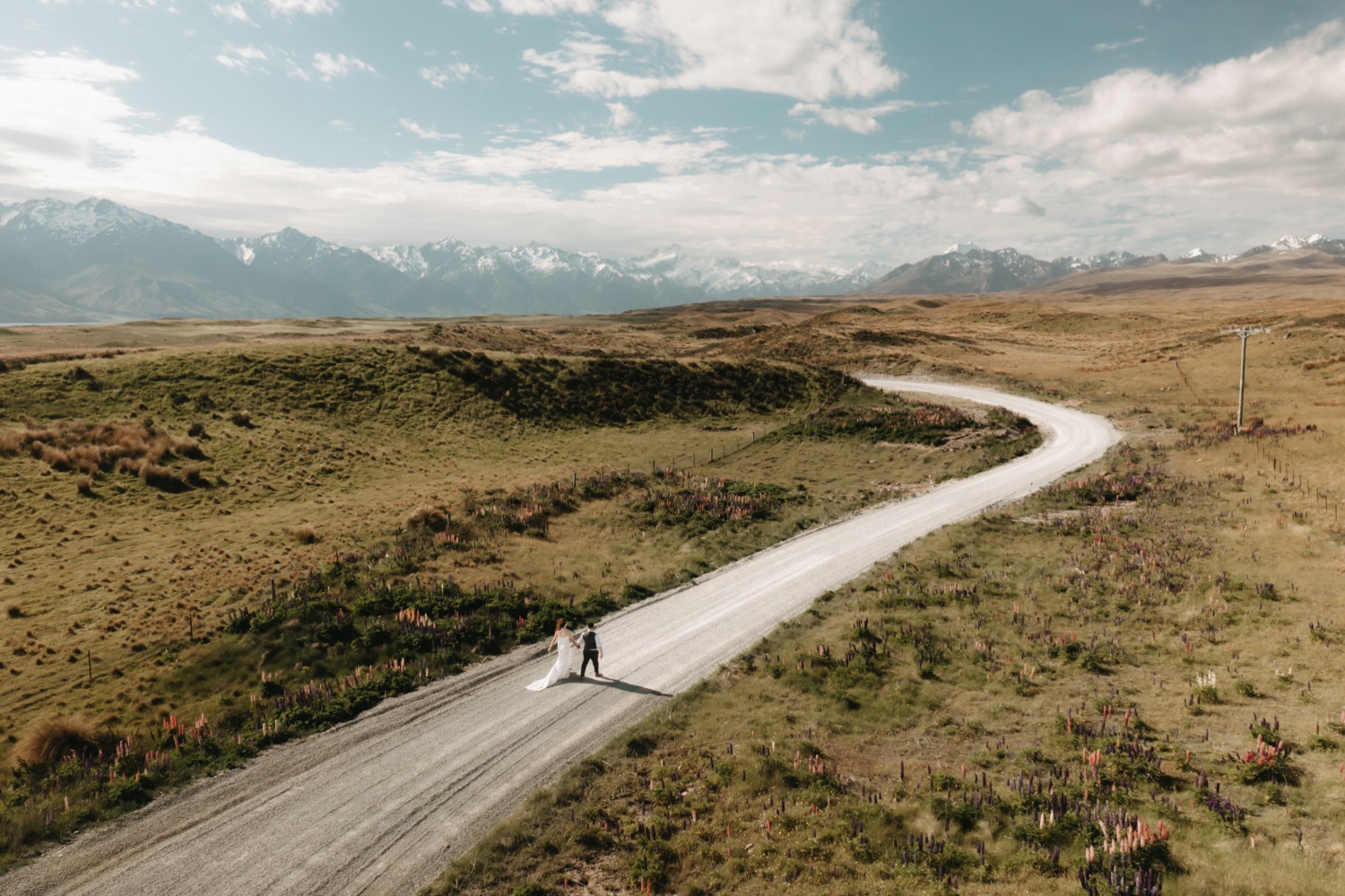 bride and groom running down dirt road towards Mount Cook National Park in New Zealand